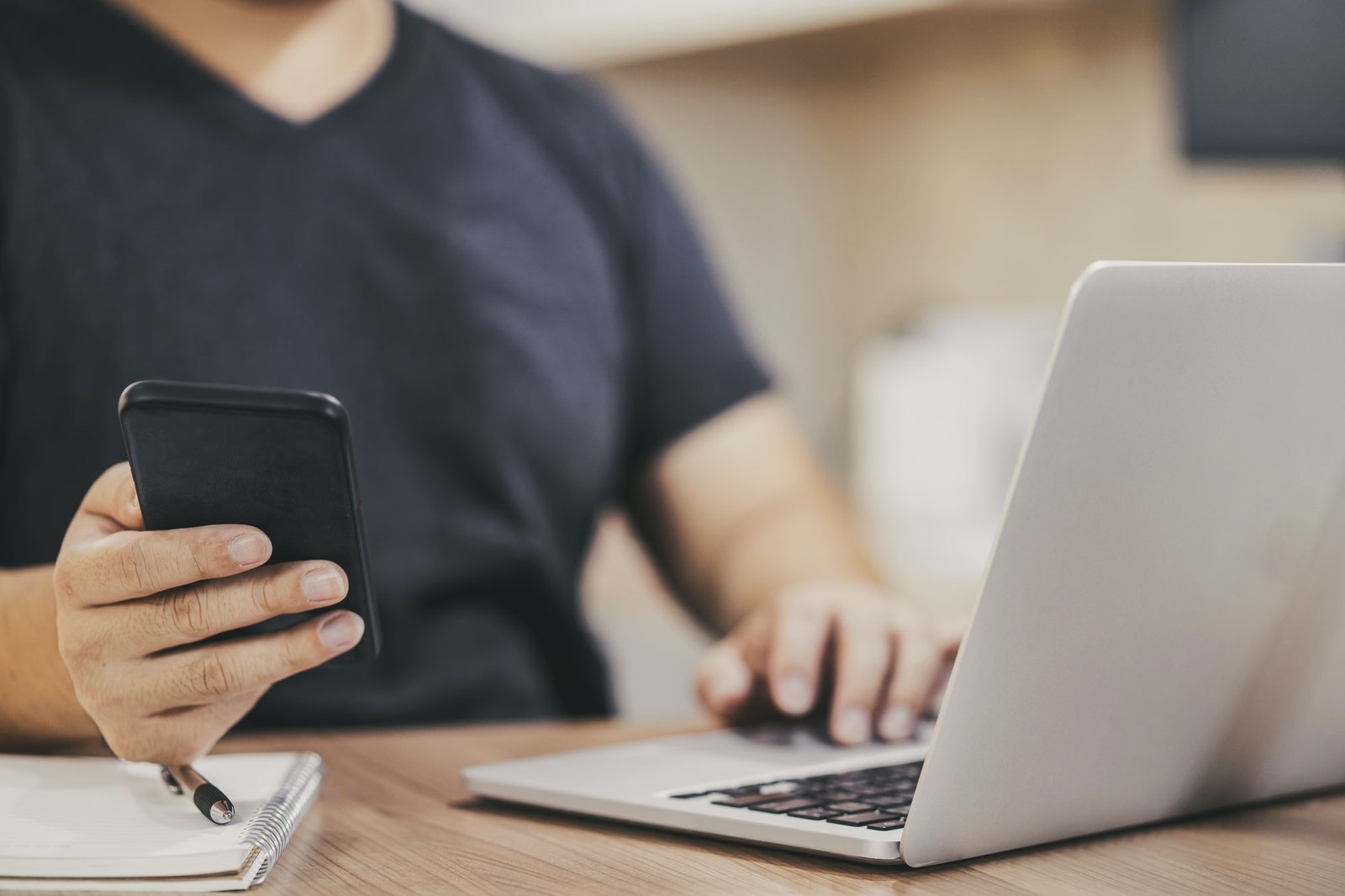 closeup-asian-hand-using-mobile-phone-with-laptop-for-work-from-home-in-house.jpg